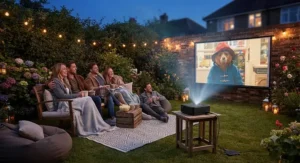 A portable laser projector under £1000 being used for an outdoor movie night in a UK garden.