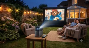 A mini garden cinema projector displaying a bright image onto an outdoor screen at dusk
