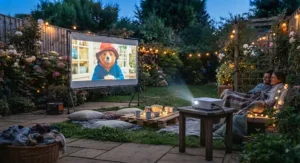 Atmospheric evening shot of a garden cinema with fairy lights, blankets, and a mini projector under £200.