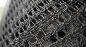 A close-up of a woven acoustic projector screen fabric showing the textured mesh construction